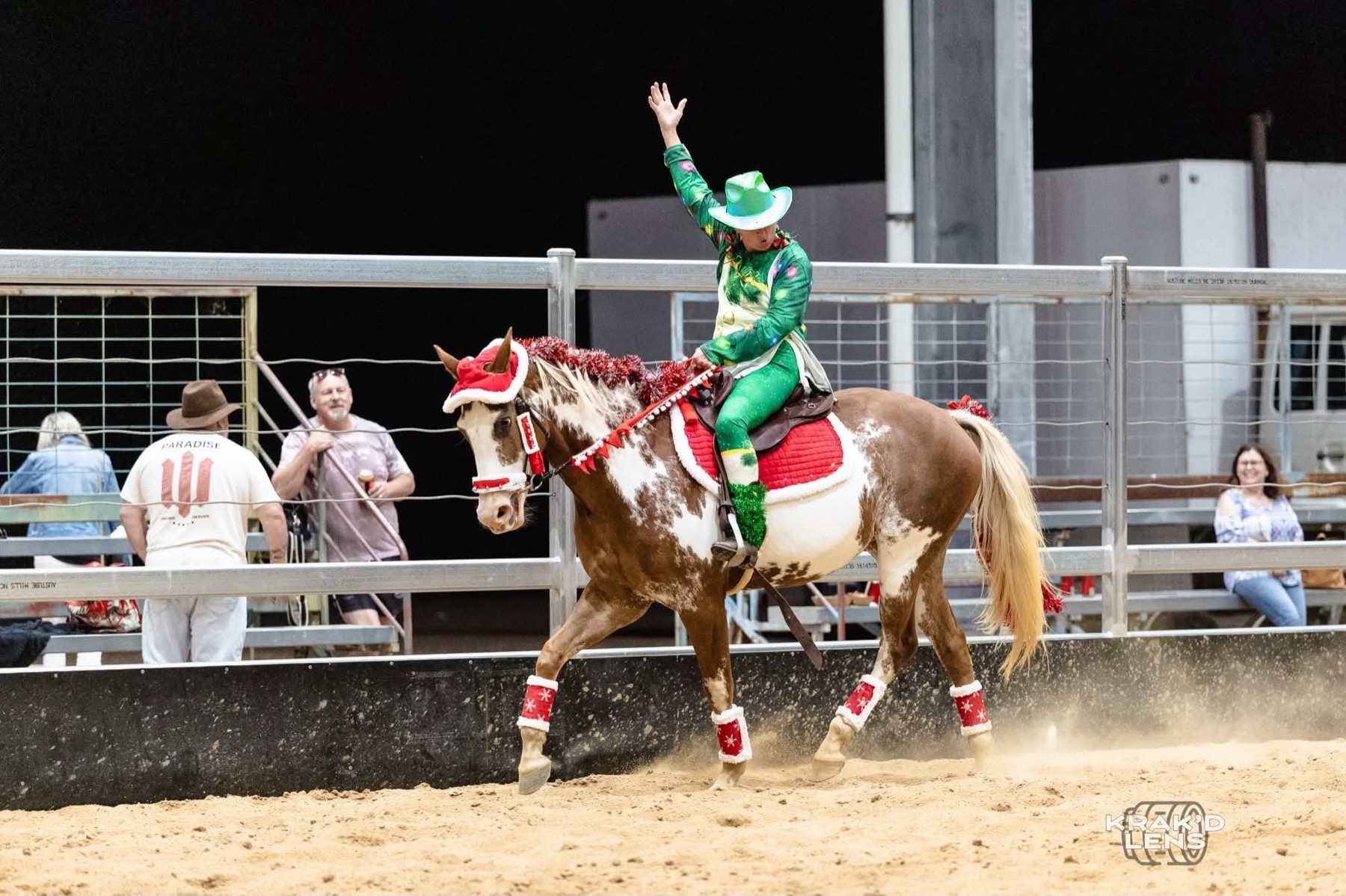 A rider in festive dress waving from horseback in an arena